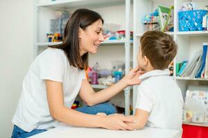 Cute woman speech therapist teaches child to pronounce words sounds and letters correctly in office photo