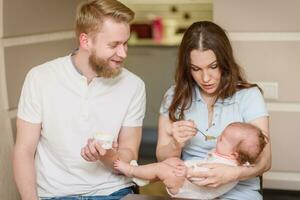 Spouses feed their naughty daughter who refuses to eat fruit puree photo