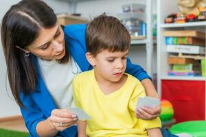 Cute woman speech therapist teaches child to pronounce words sounds and letters correctly in office photo