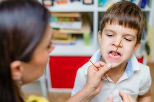 Beautiful woman speech therapist teaches boy the correct pronunciation of words and sounds in the office photo