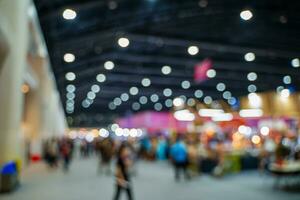 Blurred images of trade fairs in the big hall. image of people walking on a trade fair exhibition or expo where business people show innovation activity and present products in a big hall. photo