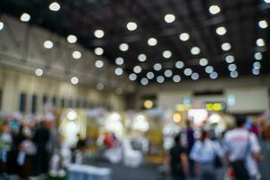 Blurred images of trade fairs in the big hall. image of people walking on a trade fair exhibition or expo where business people show innovation activity and present products in a big hall. photo