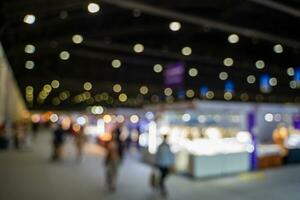 Blurred images of trade fairs in the big hall. image of people walking on a trade fair exhibition or expo where business people show innovation activity and present products in a big hall. photo