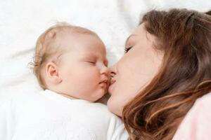 hermosa madre besos su pequeño bebé hija foto