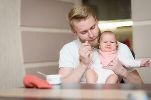 Father feeds his naughty little daughter who refuses to eat complementary foods photo