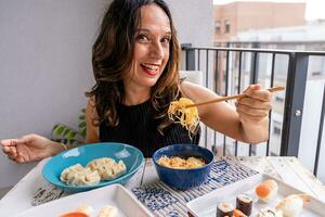 Attractive middle-aged woman eating Chinese take away food sitting at a laid table photo