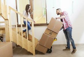 young couple carrying the boxes in new house photo