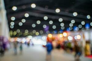 Blurred images of trade fairs in the big hall. image of people walking on a trade fair exhibition or expo where business people show innovation activity and present products in a big hall. photo