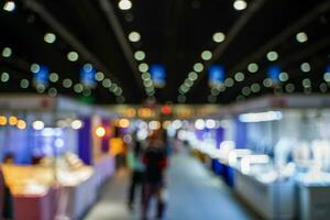 Blurred images of trade fairs in the big hall. image of people walking on a trade fair exhibition or expo where business people show innovation activity and present products in a big hall. photo