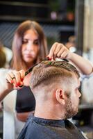 Barber cutting with scissors bearded man in barbershop photo