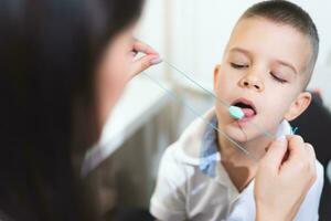 Woman speech therapist helps a boy correct the violation of his speech photo