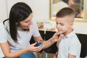 Woman speech therapist helps a child correct the violation of his speech in her office photo