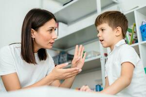 Beautiful woman speech therapist teaches boy the correct pronunciation of words and sounds in the office photo