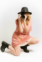 Portrait of a cute girl photographer in a hat posing with a camera in her hands in the studio on a white background photo