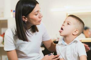 A woman speech therapist deals with the child and teaches him the correct pronunciation and competent speech. photo