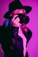 Portrait of a beautiful girl photographer in a hat who takes pictures in the studio on a fiolet background photo