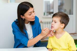 Woman speech therapist helps a boy correct the violation of his speech photo