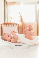 Happy baby lying on the scales in the bedroom photo