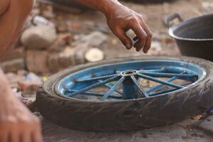 un indonesio Servicio trabajador es cambiando el neumático de un bicicleta carro a mano foto