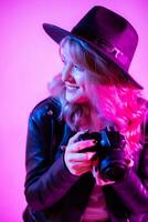 retrato de un hermosa niña fotógrafo en un sombrero quien toma imágenes en el estudio en un violeta antecedentes foto