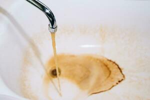 Rusty water flows from the faucet in the bathroom photo