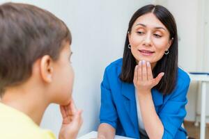 Woman speech therapist helps a boy correct the violation of his speech photo