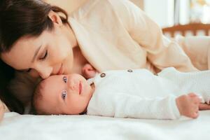 retrato de un joven mujer besos su pequeño bebé hija foto