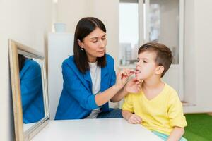 Woman speech therapist helps a boy correct the violation of his speech photo