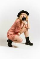 Portrait of a cute girl photographer in a hat posing with a camera in her hands in the studio on a white background photo