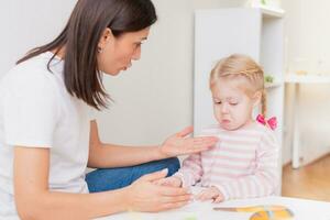 Woman speech therapist teaches a girl the correct pronunciation and literate speech photo