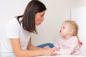 Woman speech therapist helps cute girl to learn correct pronunciation and literate speech photo