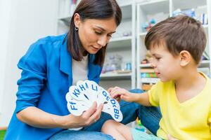 A cute boy with a speech therapist is taught to pronounce the letters, words and sounds. photo