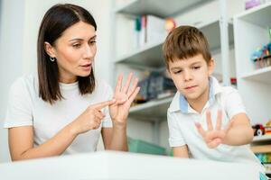 Beautiful woman speech therapist teaches boy the correct pronunciation of words and sounds in the office photo