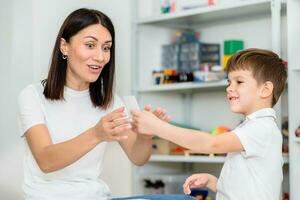 un linda niño con un habla terapeuta es enseñado a pronunciar el letras, palabras y sonidos correctamente. foto