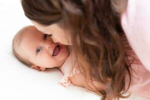 Beautiful mother kissing her little baby daughter photo