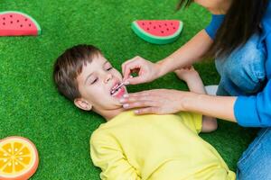 Woman speech therapist helps a child correct the violation of his speech in her office photo