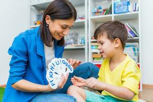 A cute boy with a speech therapist is taught to pronounce the letters, words and sounds. photo