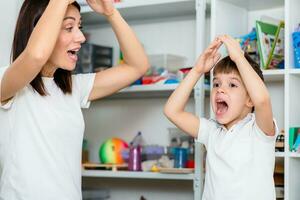 Beautiful woman speech therapist teaches boy the correct pronunciation of words and sounds in the office photo