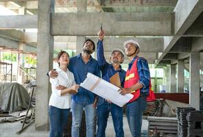 happy family visiting and talking to contractor at site,engineer or architect explain progress of a house building with construction paper to young couple,concept of business,real estate home project photo