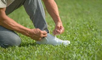 senior man tying shoelace getting ready for exercise, concept of preventing the risk of falls in the elderly photo