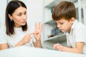 Beautiful woman speech therapist teaches boy the correct pronunciation of words and sounds in the office photo