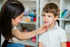 A beautiful woman speech therapist deals with the boy and teaches him the correct pronunciation and competent speech. photo