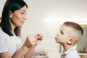 Woman speech therapist helps a boy correct the violation of his speech photo