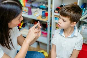 Beautiful woman speech therapist teaches boy the correct pronunciation of words and sounds in the office photo