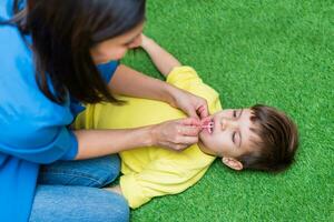 A woman speech therapist deals with a boy and performs an exercise to correct the speech apparatus by playing on the floor photo