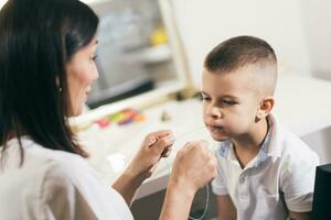 Woman speech therapist helps a boy correct the violation of his speech photo