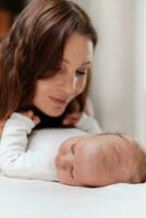 Young woman taking care of her sleeping baby daughter in the bedroom photo