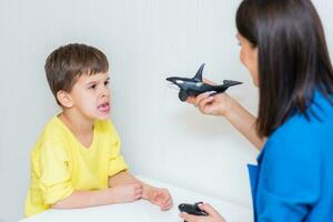 Cute woman speech therapist teaches child to pronounce words sounds and letters correctly in office photo