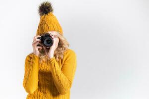 Portrait of a beautiful girl photographer in a knitted hat who takes pictures in the studio photo