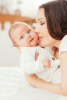 Beautiful mother kissing her little baby daughter photo